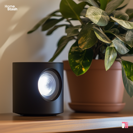 Compact blackmini projector on a wooden shelf next to a potted plant, emitting soft light. Integrates seamlessly in a minimalist and cozy atmosphere with warm natural tones.