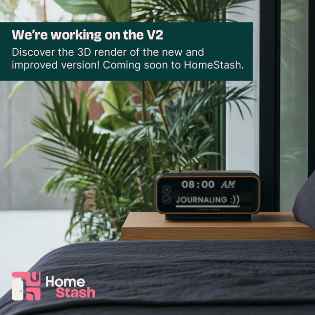 A habit tracking clock displayed on a wooden bedside table next to a bed with dark gray bedding. The clock shows "08:00 AM" and "JOURNALING :))" on its screen. Lush green plants are visible through a large glass window in the background, creating a serene and natural ambiance.
