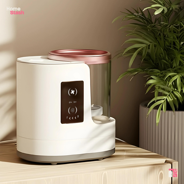 Electric makeup brush cleaner and dryer with a sleek white and rose gold design, shown on a wooden surface beside a potted plant, ideal for quick, hygienic brush care.
